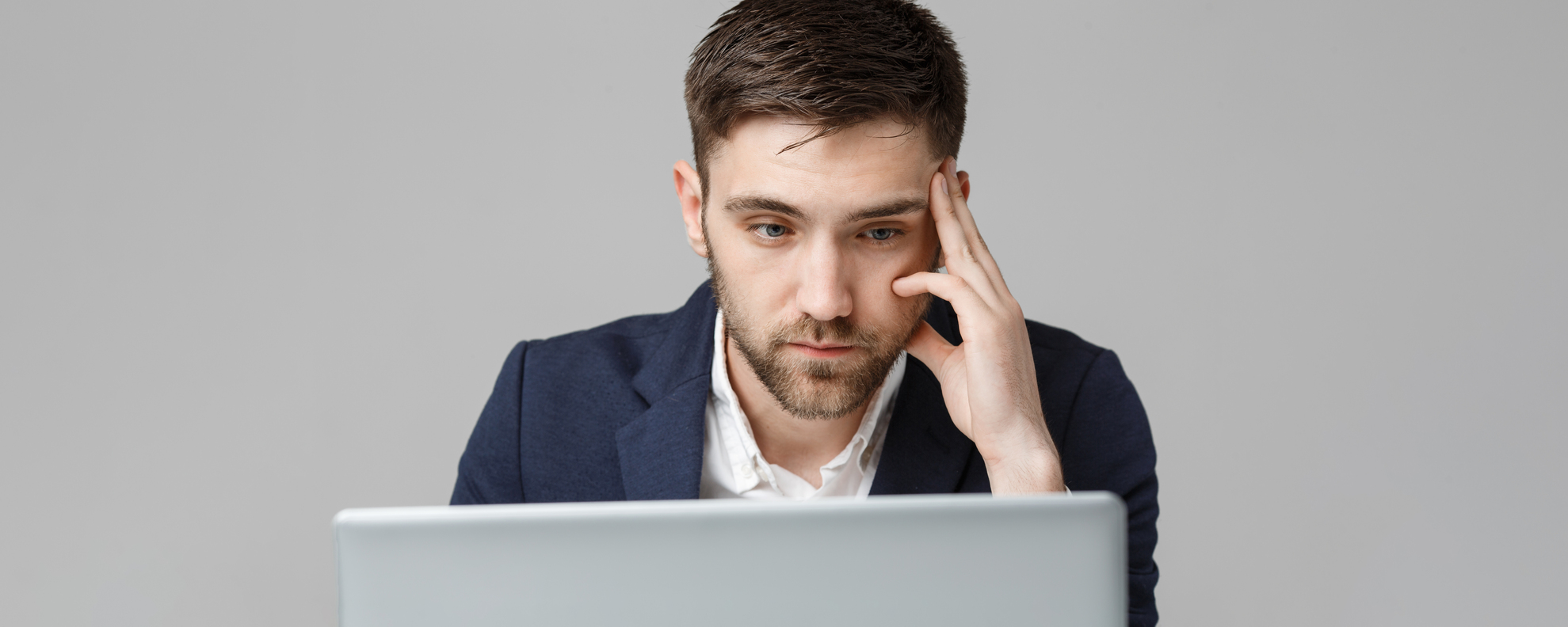 Business Concept – Portrait handsome serious business man in suit looking at laptop. White Background.
