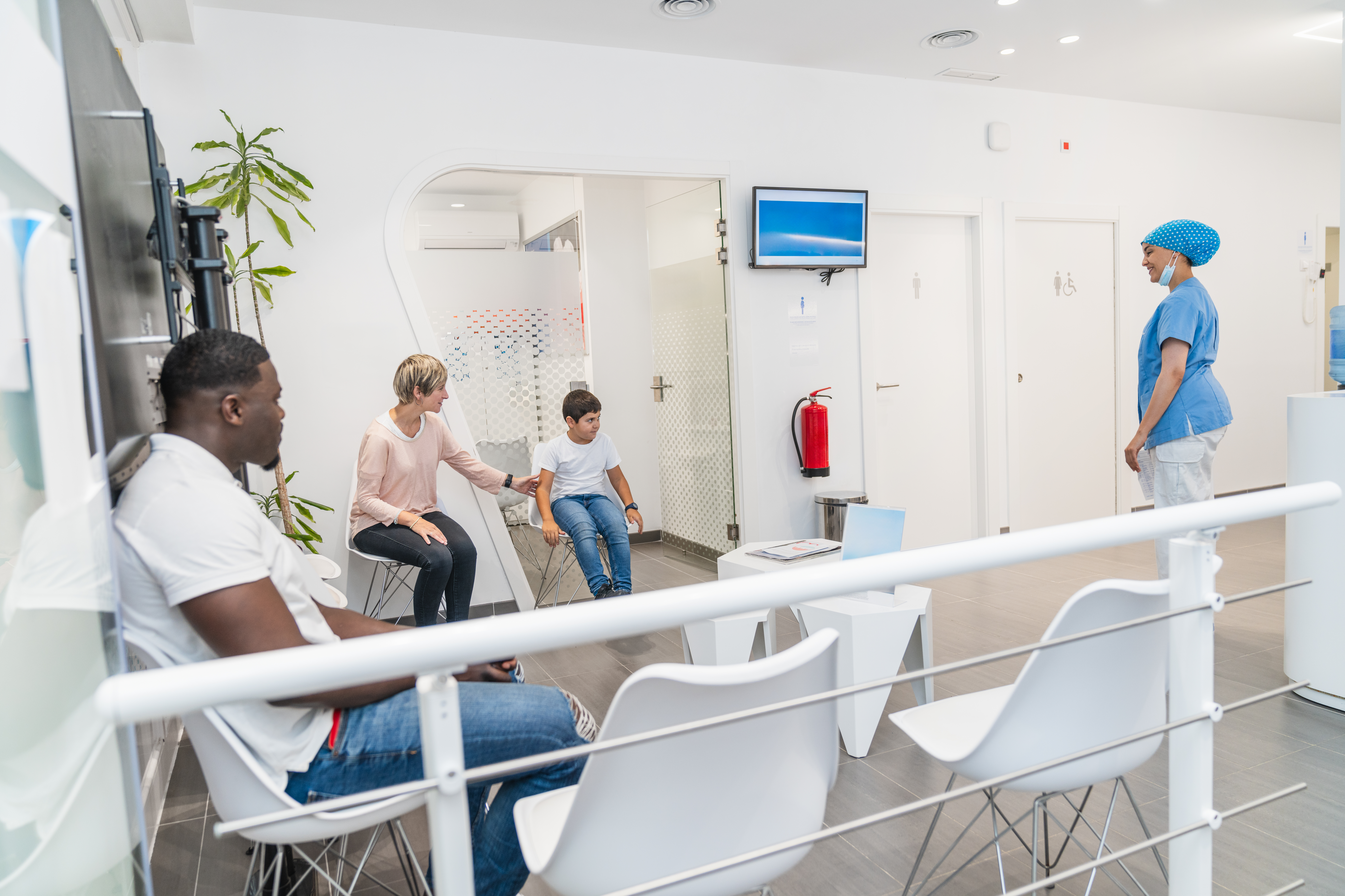 Featured image of modern clinic with token screen and staff using queue management software